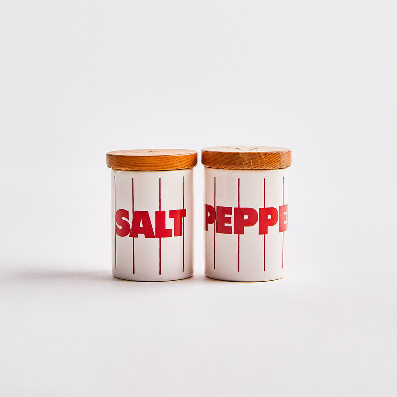 White with red lines and text salt and pepper shakers with wood top.