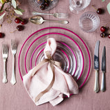 Top view of mixed pink table setting with gold cutlery surrounded by glassware on a pink tablecloth.