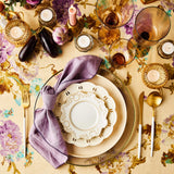 Top view of table setting surrounded by candles, glassware on floral and cream tablecloth.