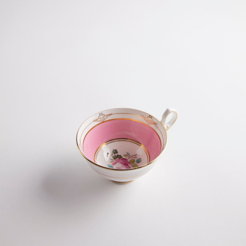Pink tea cup with gold and floral vintage design.