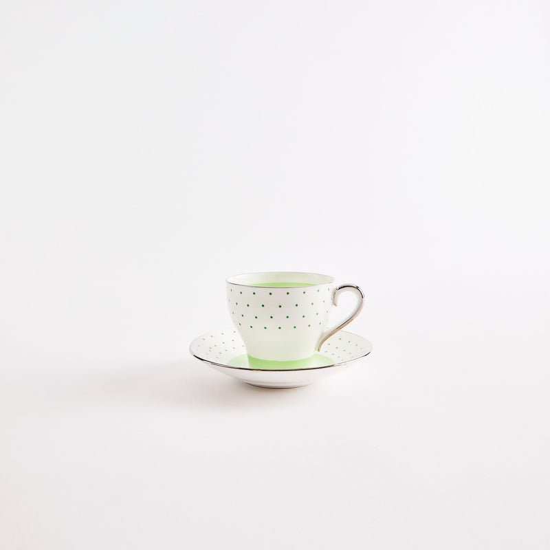 White teacup and saucer with green polka dot design.