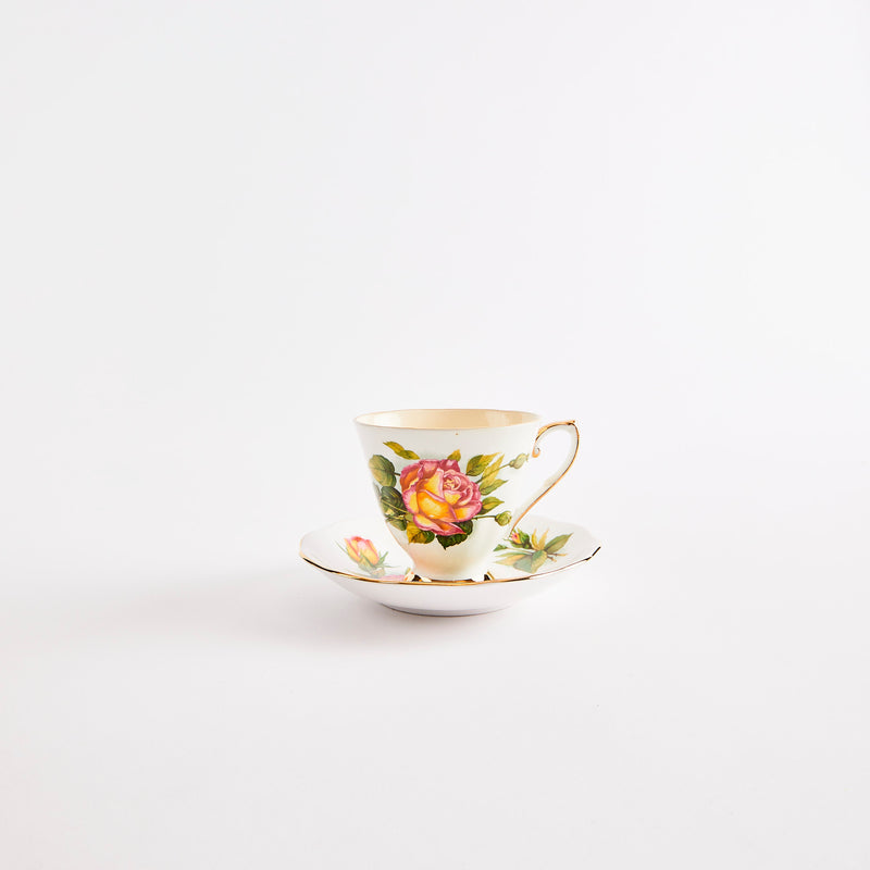 White teacup and saucer with gold rim and mulitcolour floral design.