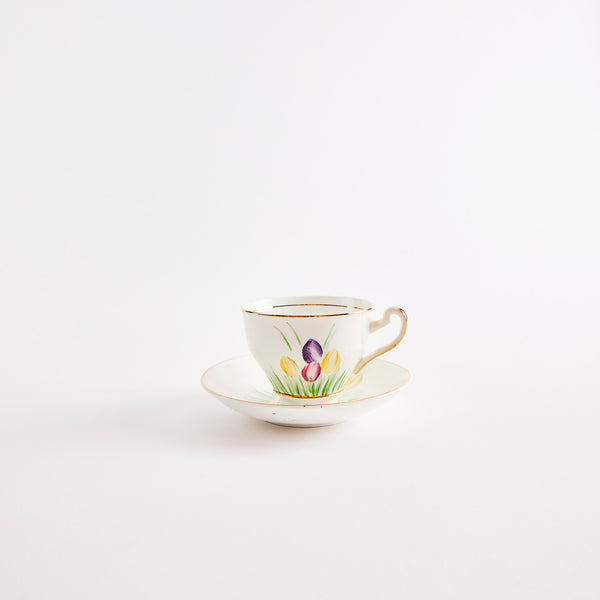 White teacup and saucer with gold rim and mulitcolour tulip design.