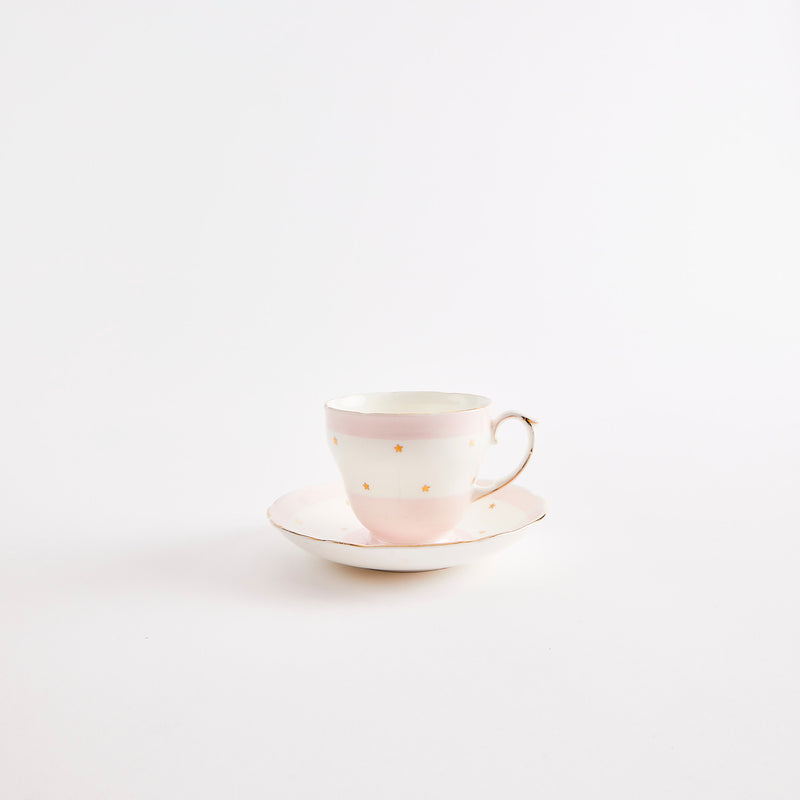 White and pink teacup and saucer with gold star pattern.