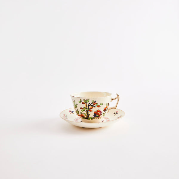 White teacup and saucer with gold rim and mulitcolour floral design.