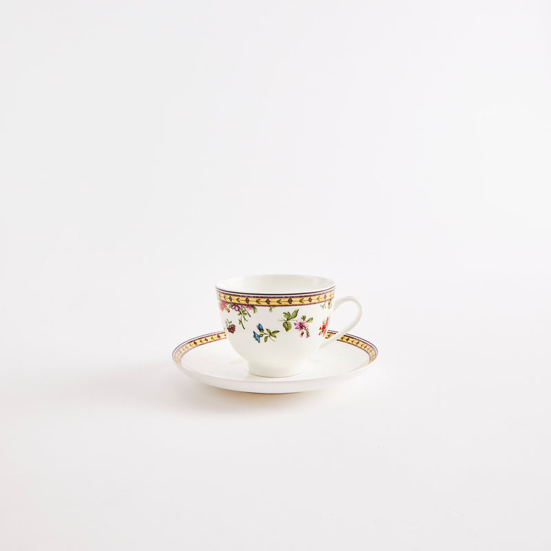 White teacup and saucer with multicolour floral design.
