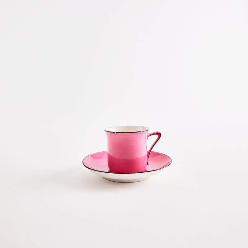 Pink teacup and saucer with black rim.
