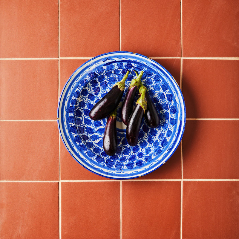 Top view of eggplants on blue plate and orange tiled background.