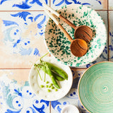 Top view of mixed green bowls on mixed orange and blue designed tile.