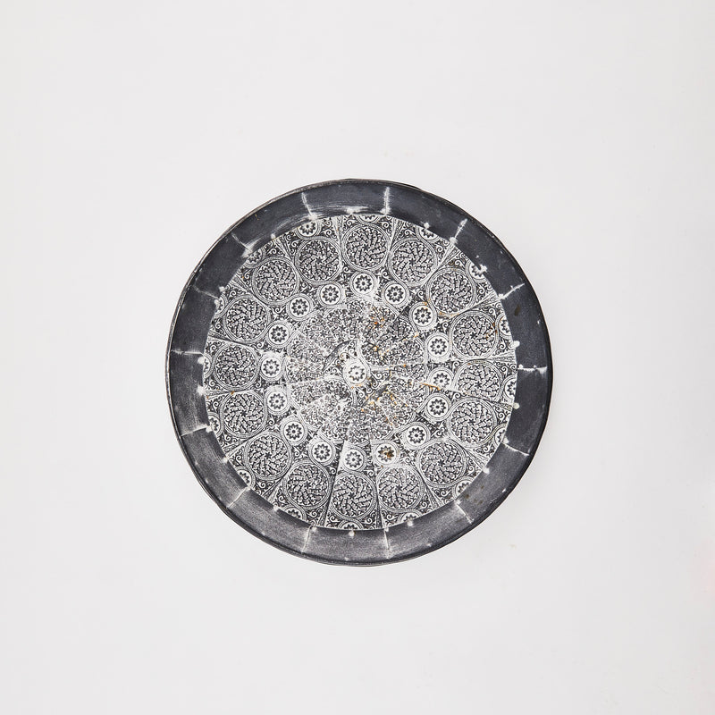 Grey metal circular tray with spiral detail.