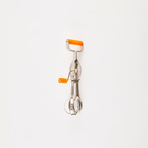 Silver vintage hand whisk with orange handles.