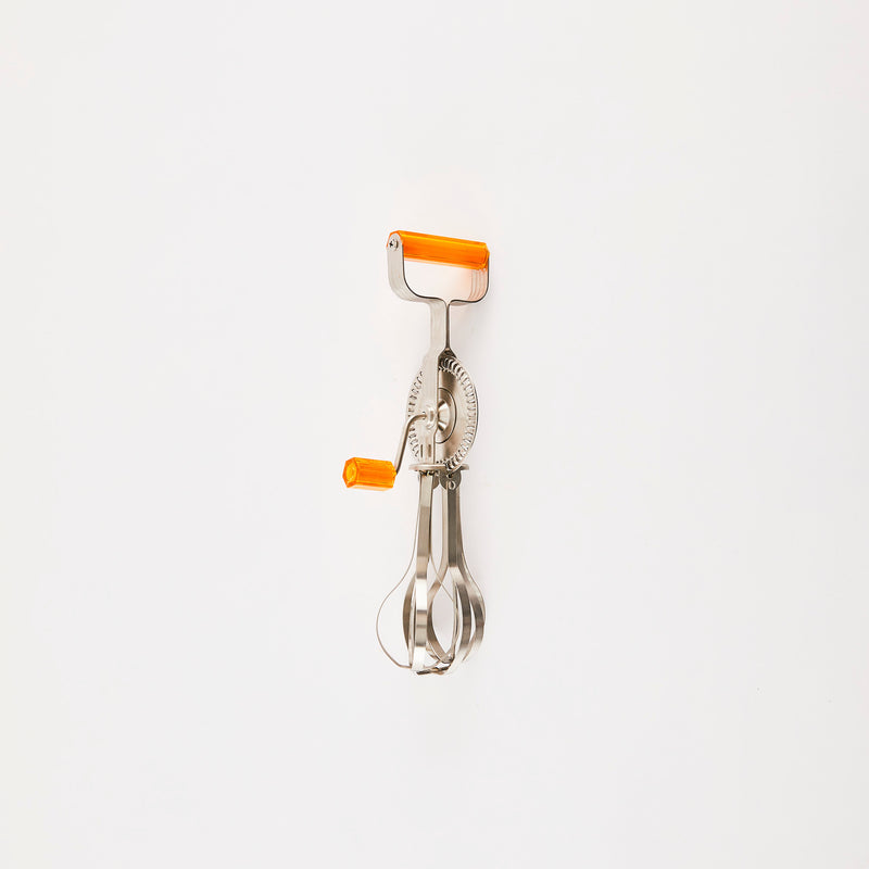 Silver vintage hand whisk with orange handles.