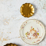 Top view of floral and gold plates on White Gold Background.