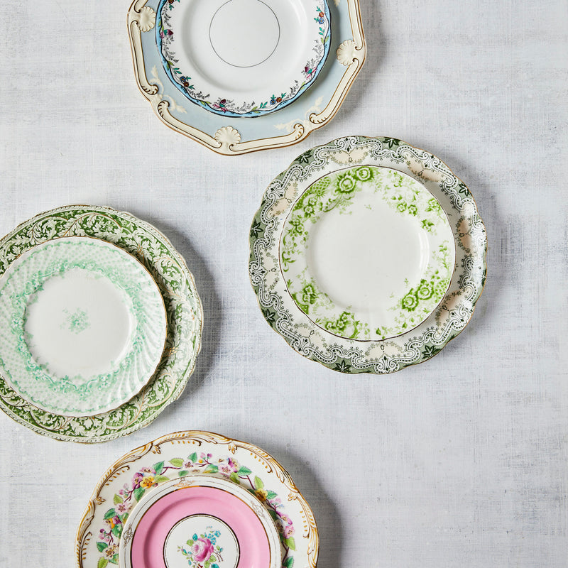 Top view of mixed vintage plates on White Linen Background.